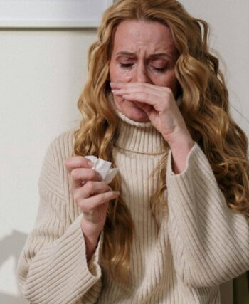 Woman itching nose holding tissue