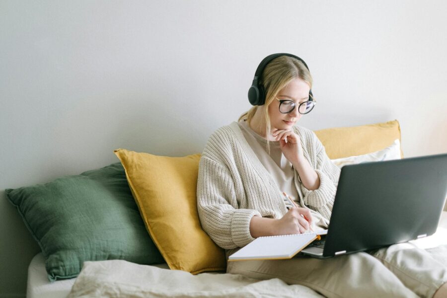 woman wearing headphones and typing on laptop