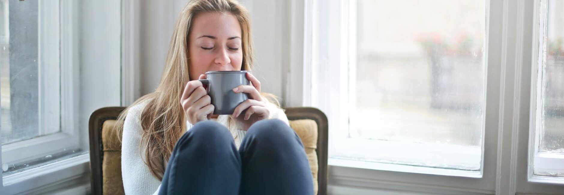 woman sitting in chair drinking coffee