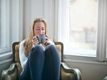 woman sitting in chair drinking coffee