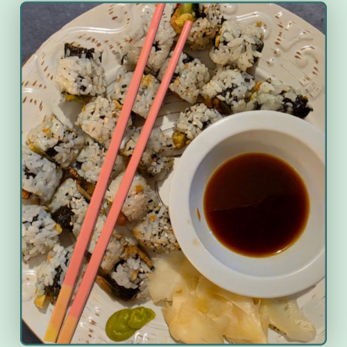 Overview of sushi rolls with pink chopsticks and soy sauce